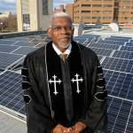 Rev. Dr. Earl D. Trent Jr., Senior Pastor at Florida Avenue Baptist Church in Washington, DC stands among the solor panels that are on top of the church roof. Photo/Jocelyn Augustino/Urban News Service.