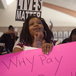 A woman holds a sign during a recent Flint, Mich., city council meeting. Photo/Andre Smith/Michigan Chronicle.